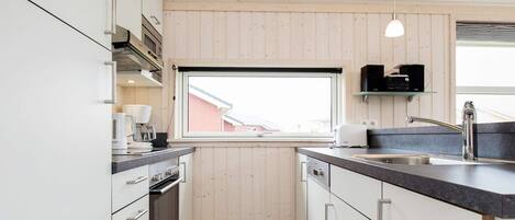 A modern kitchen with white cabinets, a black countertop, and a window providing a view of the outside.
