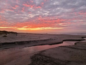A beach with a water channel and dunes.