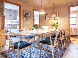 A room with a wooden interior, a round dining table with chairs, a bed, and a shower area.