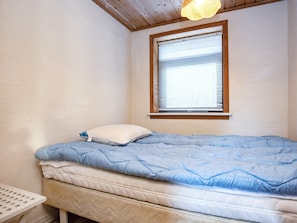 A bedroom with a bed, a window with blinds, and a ceiling light fixture.