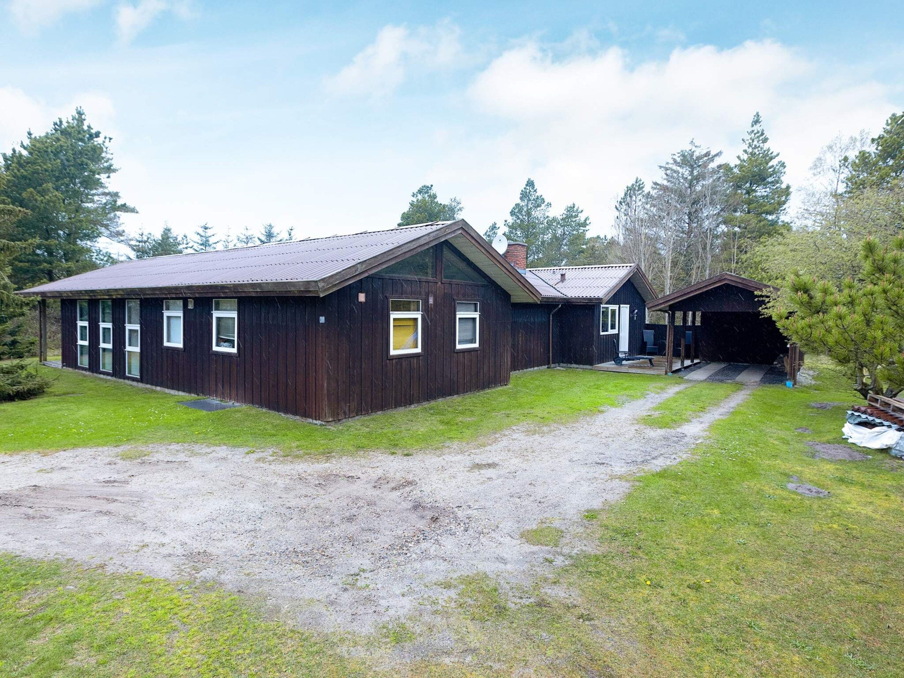A wooden cabin with a gravel driveway, a covered porch, and a garage.