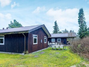 Eine Holzhütte mit überdachter Sitzterrasse und einem Rasen.