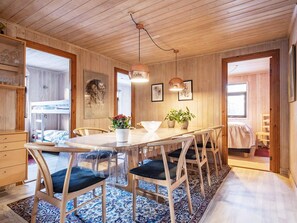 A wooden interior with a dining table, chairs, and a bunk bed.