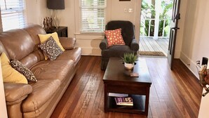 Un salon avec un canapé en cuir marron, un fauteuil noir et une table basse en bois.