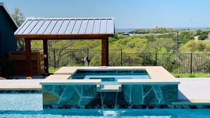 Una piscina con una fuente de piedra y un pérgola de madera.