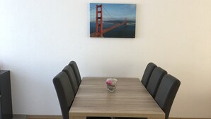 Ein Esstisch mit vier Stühlen, eine Vase mit Blumen und ein Gemälde der Golden Gate Bridge an der Wand.