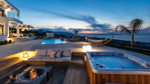 Uma área de piscina externa luxuosa, com hidromassagem, lareira e rede.