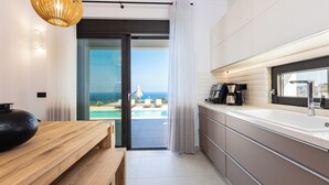 Cozinha moderna com uma ilha grande, vista para o oceano e porta de vidro deslizante que dá para uma varanda.