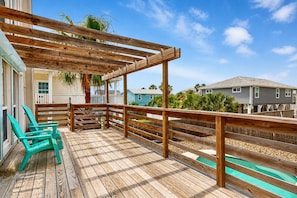 A wooden deck with a pergola, a pool, and a view of neighboring houses.