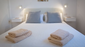 Una cama bien hecha con dos almohadas, cabecero y dos mesitas de noche con lámparas.
