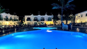 Piscina de color azul, rodeada por una cerca y palmeras.