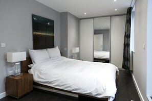 Relax in a serene space with a large bed, nightstand, and mirror.