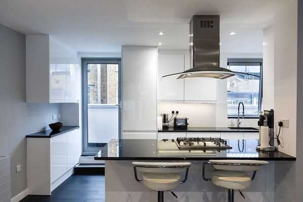 Enjoy cooking in this kitchen with a sleek island, bar stools, and stainless steel range hood.
