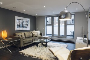Relax in this inviting living space with a comfortable sofa, glass coffee table, and large window offering a view of the outside.
