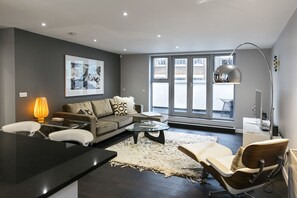 Relax in a stylish living space with a sofa, chairs, and dining table, offering a city view and ample natural light.