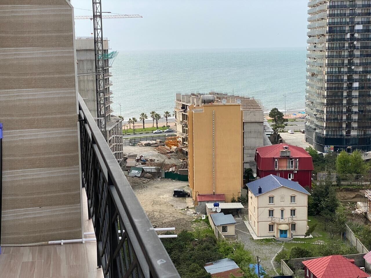 Eine Küstenansicht mit Strand, einer Baustelle und einem Gebäude mit rotem Dach.
