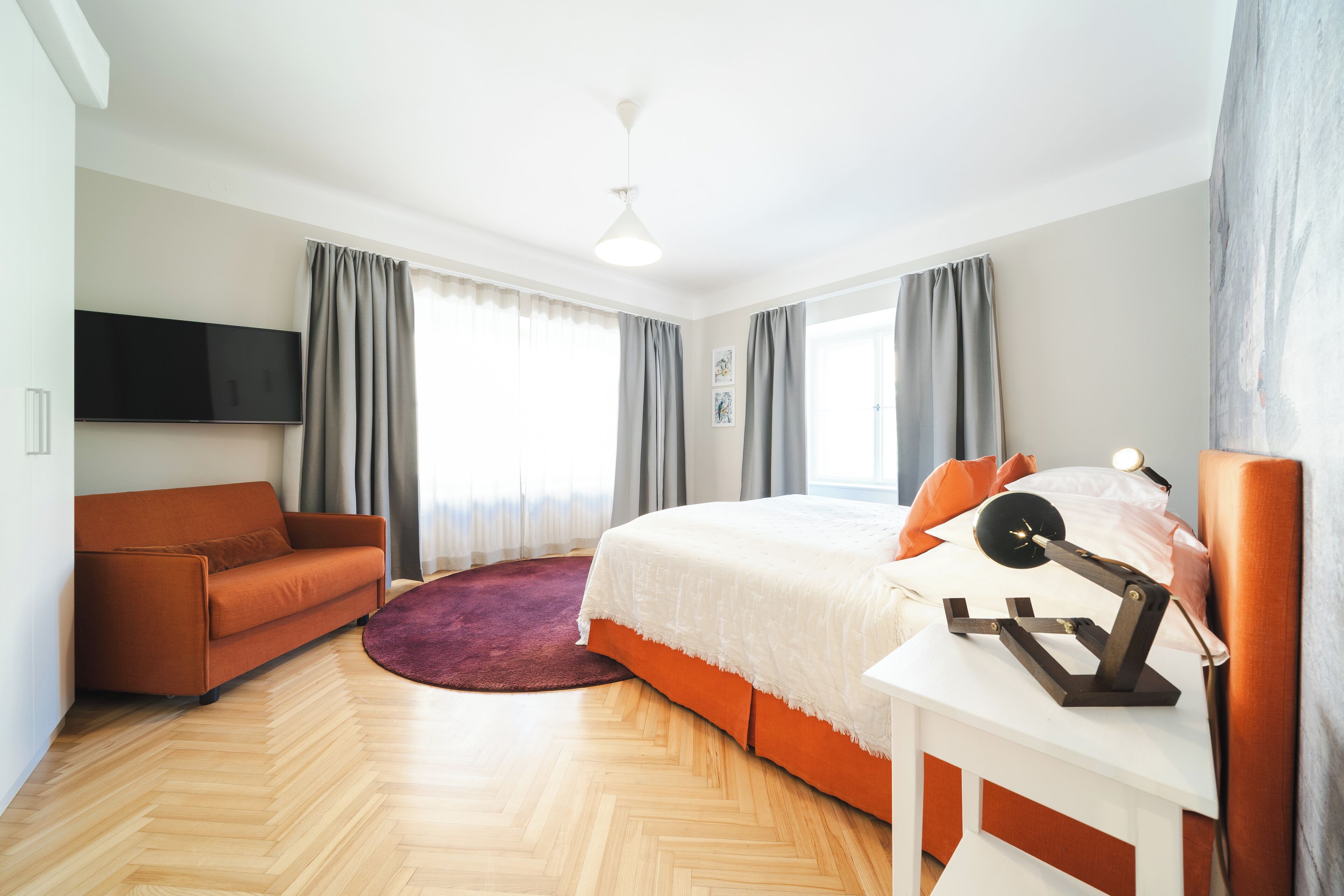 Un dormitorio moderno con cama, sofá, televisión y ventilador de techo.