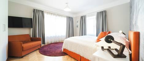 Un dormitorio moderno con cama, sofá, televisión y ventilador de techo.