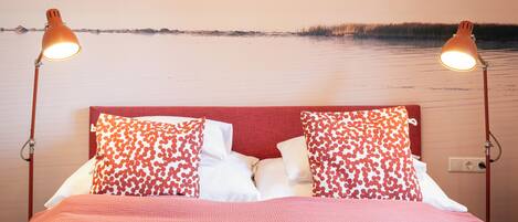 A bed with a red headboard, two bedside lamps, and pillows with a red and white pattern.