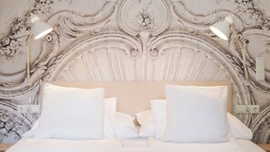 A bed with white linens and a decorative headboard with intricate carvings. - GrazRentals (Graz)