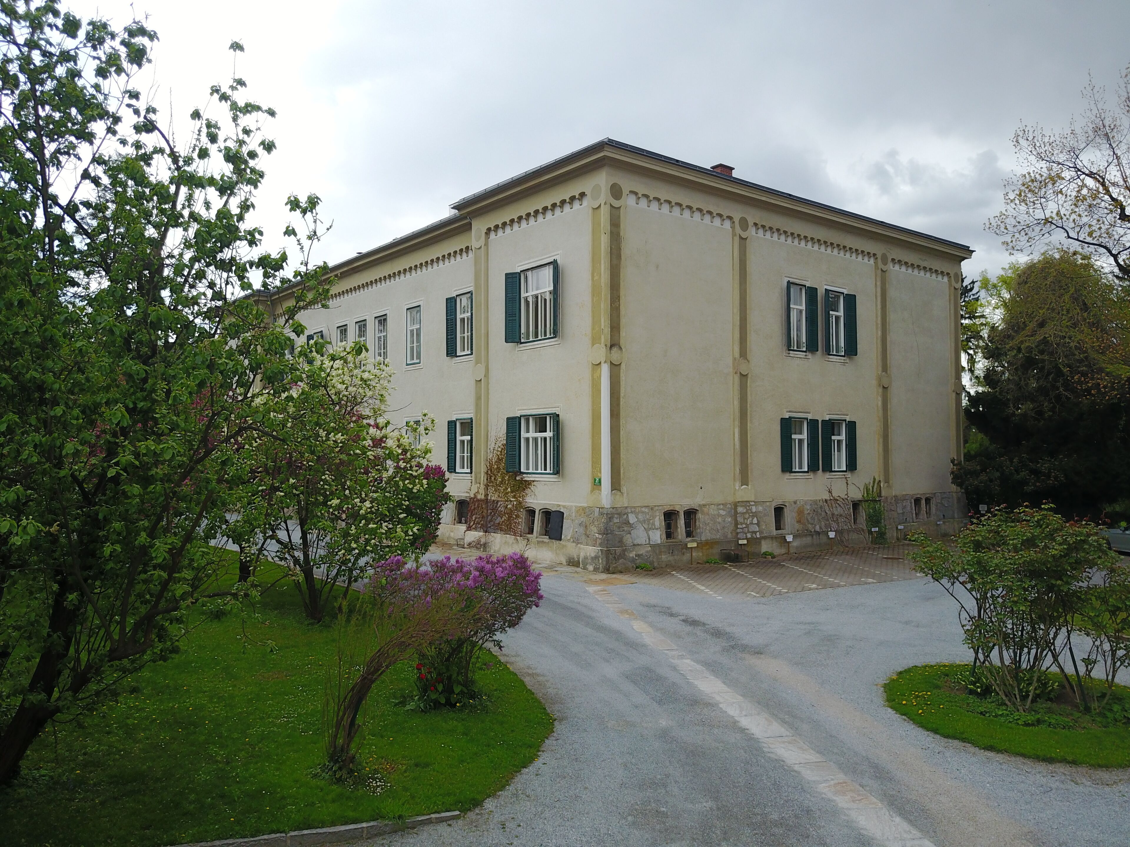 A large building with a symmetrical facade, multiple windows with shutters, and a central entrance.