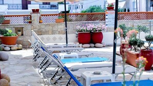 A terrace with sun loungers, potted plants, and a stone wall. - Melis Studios (Kassandra)