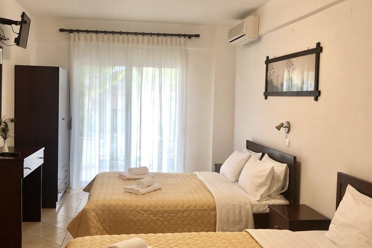 A hotel room with two beds, a desk, and a window with curtains.