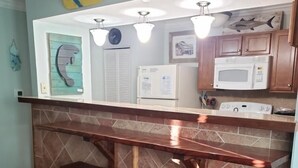 A kitchen with a bar area, a microwave, a refrigerator, and a clock on the wall. - Coastal Sands located @ Gulf Terrace Condos in Destin! Sleeps 6 ~ 1BR & 1-1/2 BA (Destin)