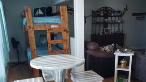 A rustic dining area with a wooden table and benches, a bunk bed in the background, and a cozy living space with a sofa and decorative items. - Coastal Sands located @ Gulf Terrace Condos in Destin! Sleeps 6 ~ 1BR & 1-1/2 BA (Destin)
