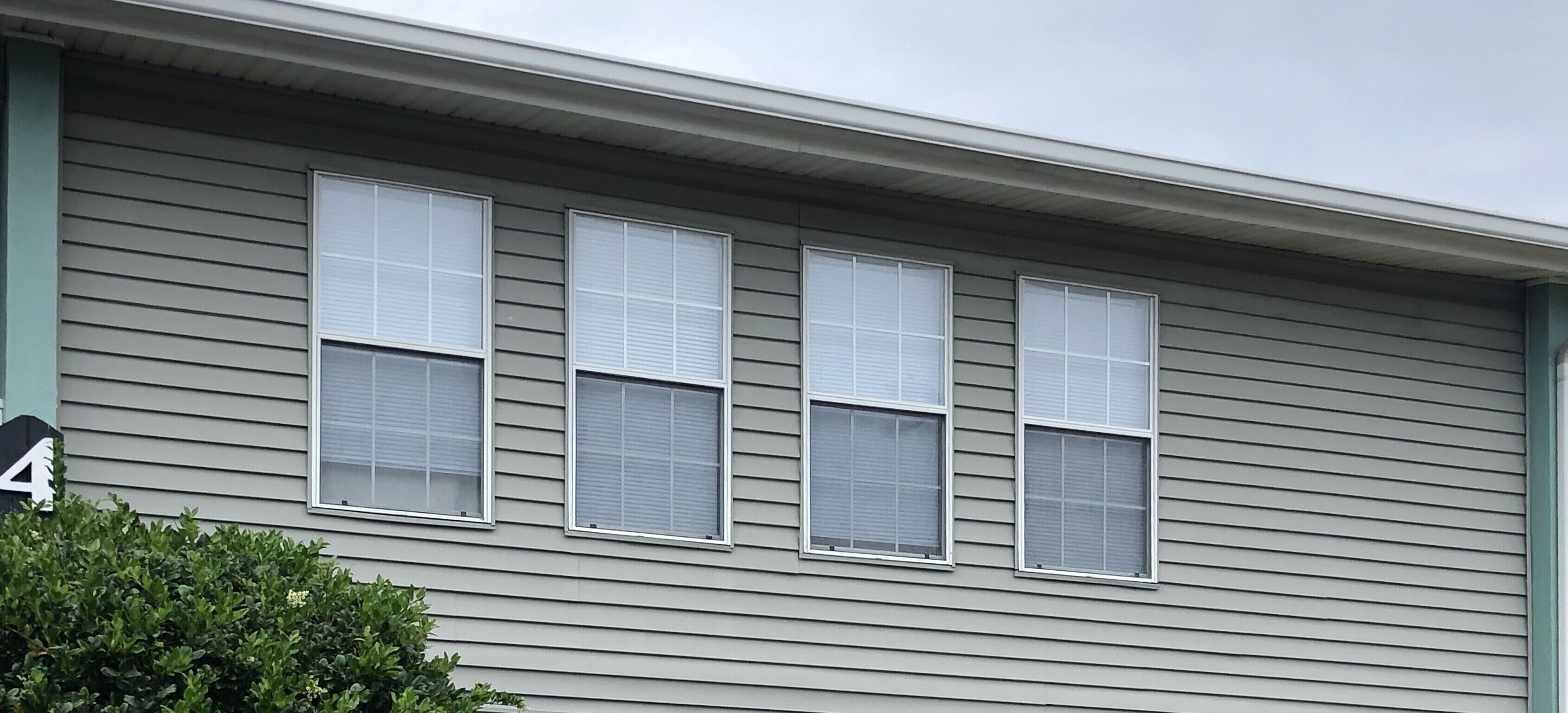 A building with four windows, each with a white frame and a horizontal blinds.