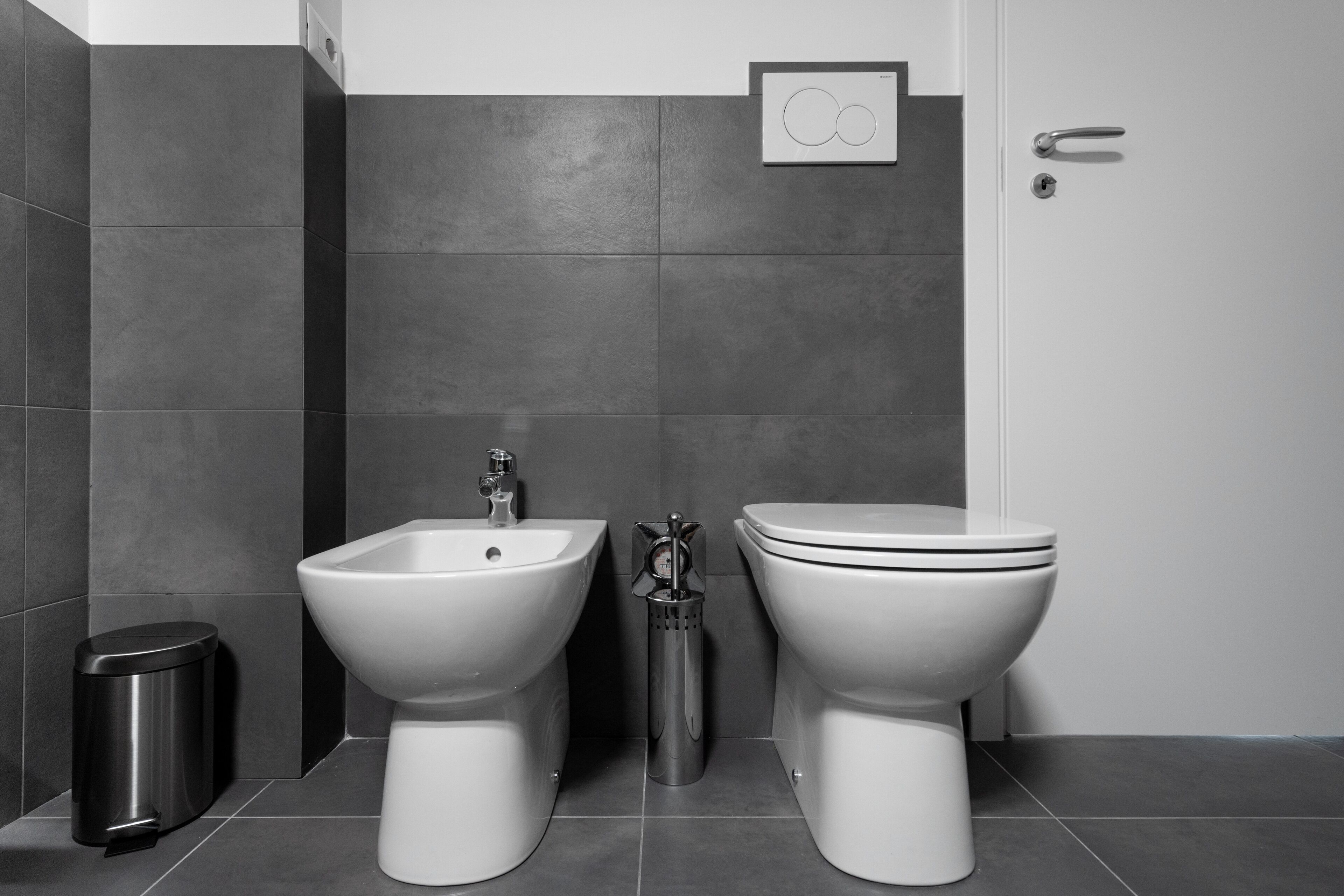 Un baño moderno con bidé, inodoro y cubo de basura.