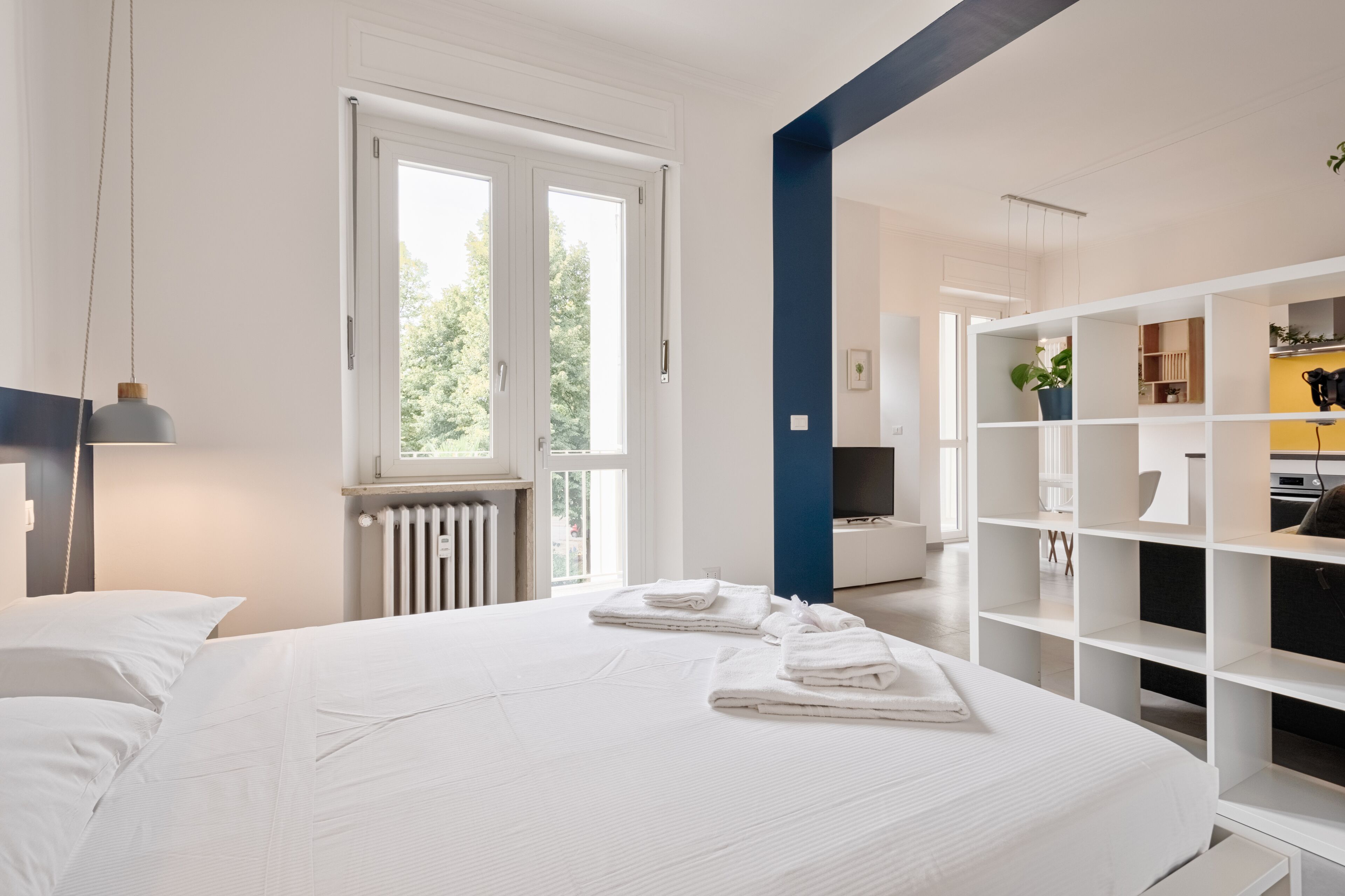 Un dormitorio moderno con una cama grande, un armario blanco y vistas al exterior a través de una ventana.