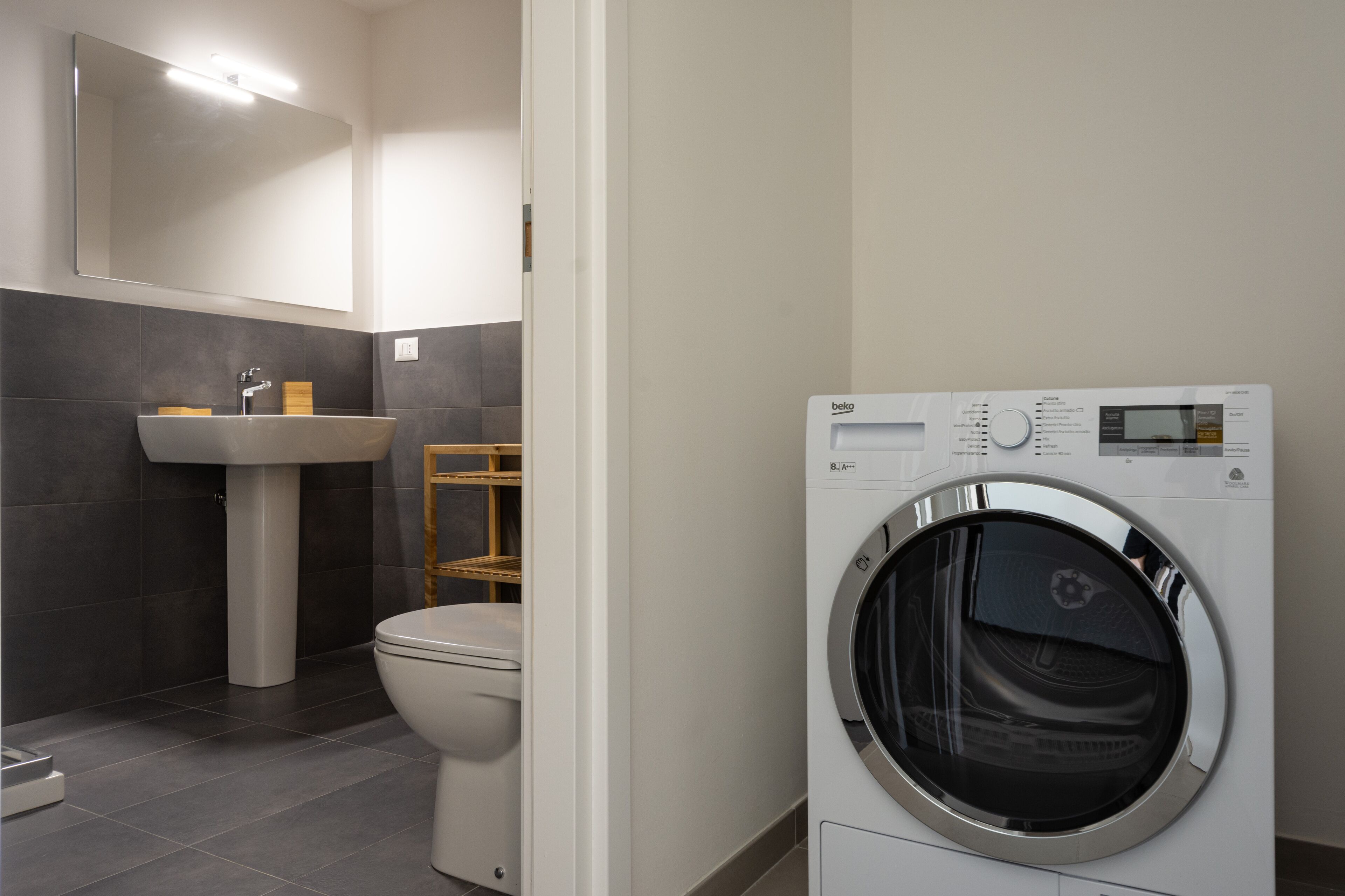 Een moderne badkamer met een wastafel, toilet en een voorlader wasmachine.