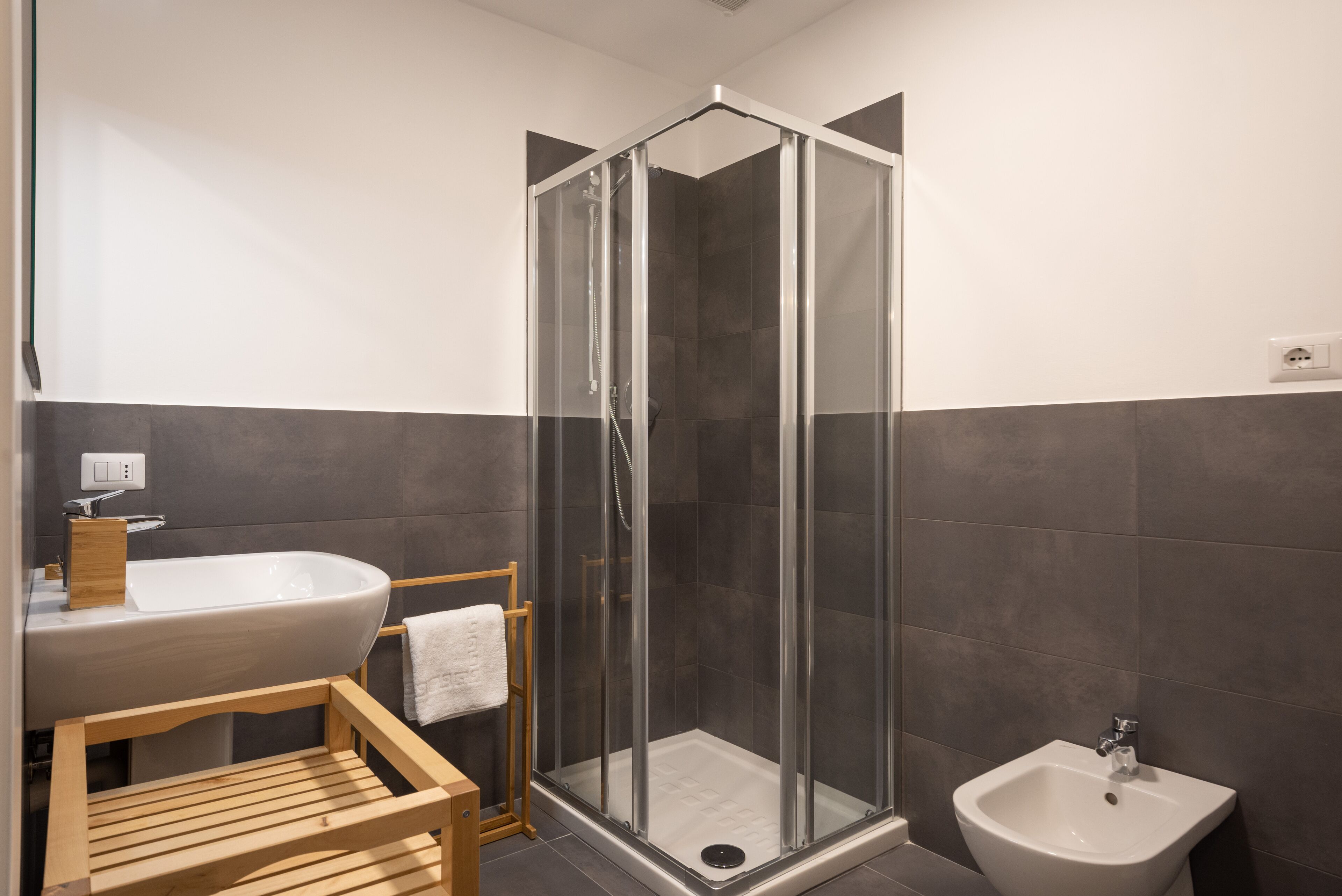 Ein modernes Badezimmer mit einer gläsernen Duschkabine, einem Holzwaschtisch und einem Bidet.