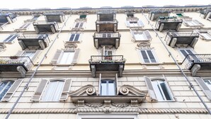 A multi-story building with a classic architectural style, featuring ornate balconies and a central entrance with a wooden door.
