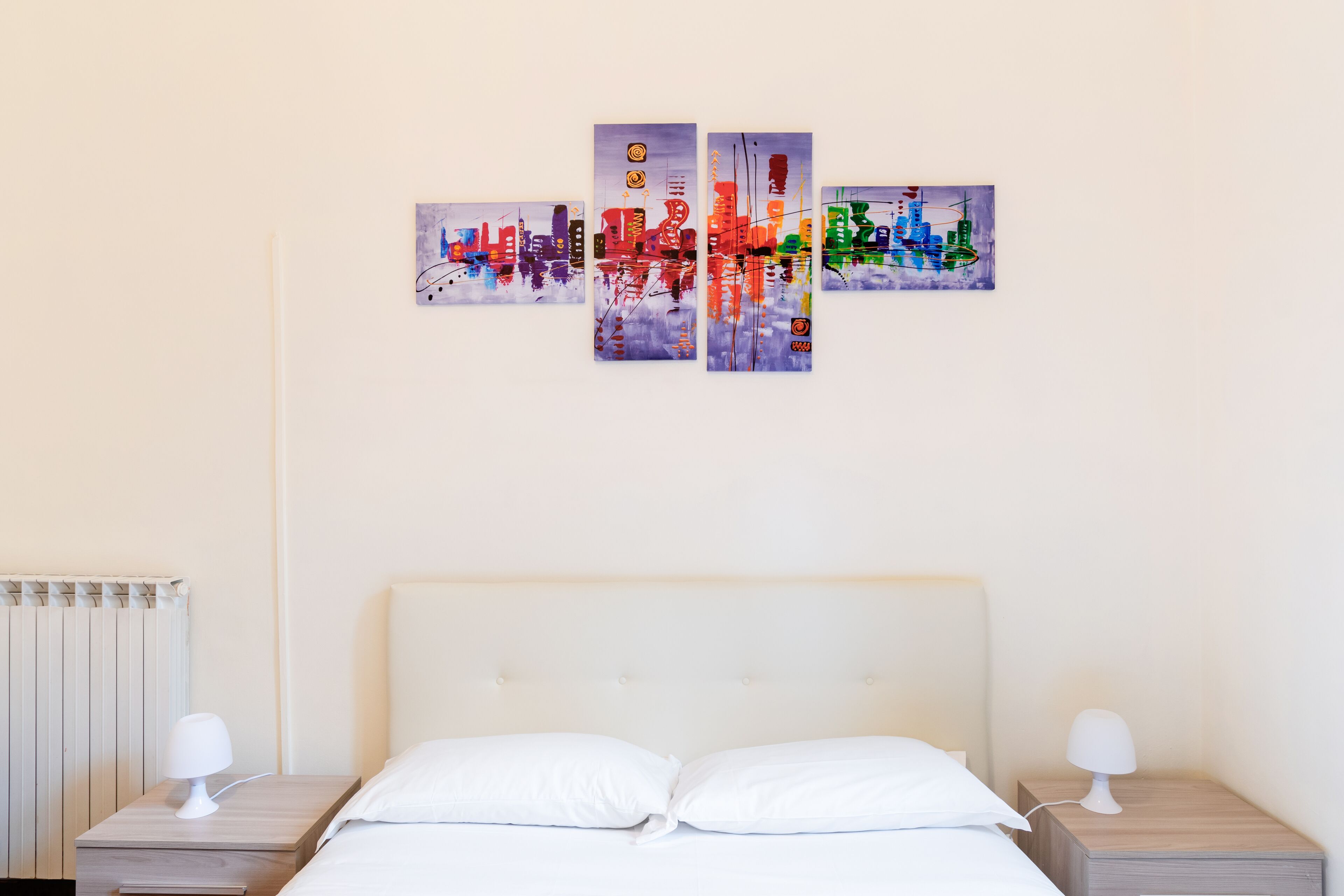 A hotel room with a bed, two bedside tables, and a wall-mounted artwork.