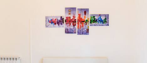 A hotel room with a bed, two bedside tables, and a wall-mounted artwork.
