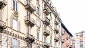 A multi-story building with balconies, ornate architectural details, and a row of windows with shutters.