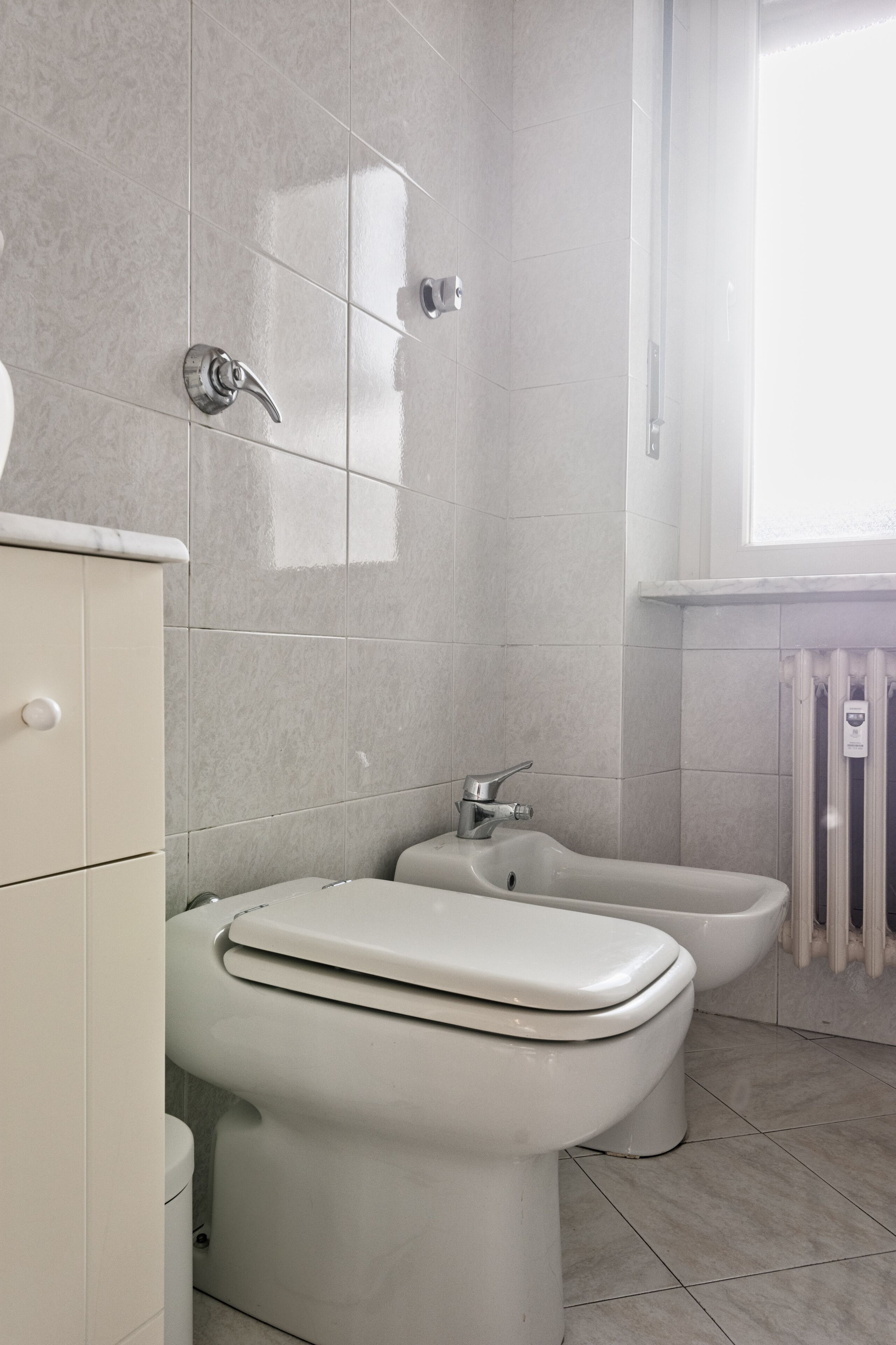 A modern bathroom with a toilet, bidet, and a radiator.