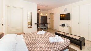 Quarto de hotel com cama, escrivaninha, televisão e guarda-roupa.