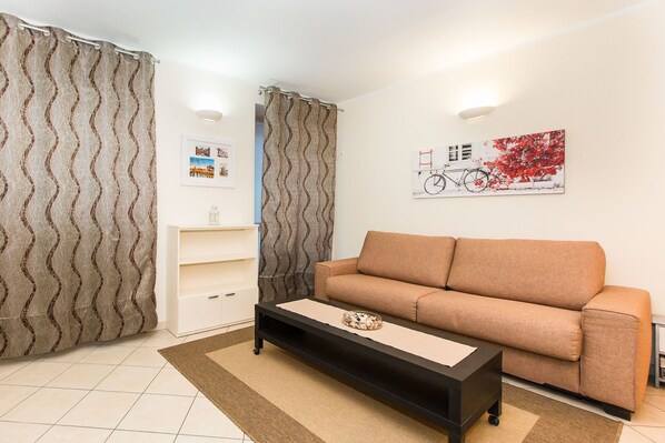Un salon avec un canapé, une table basse, une bibliothèque et un tableau accroché au mur.
