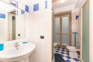 Une salle de bain avec un lavabo blanc, un miroir et un sol à carreaux bleus.
