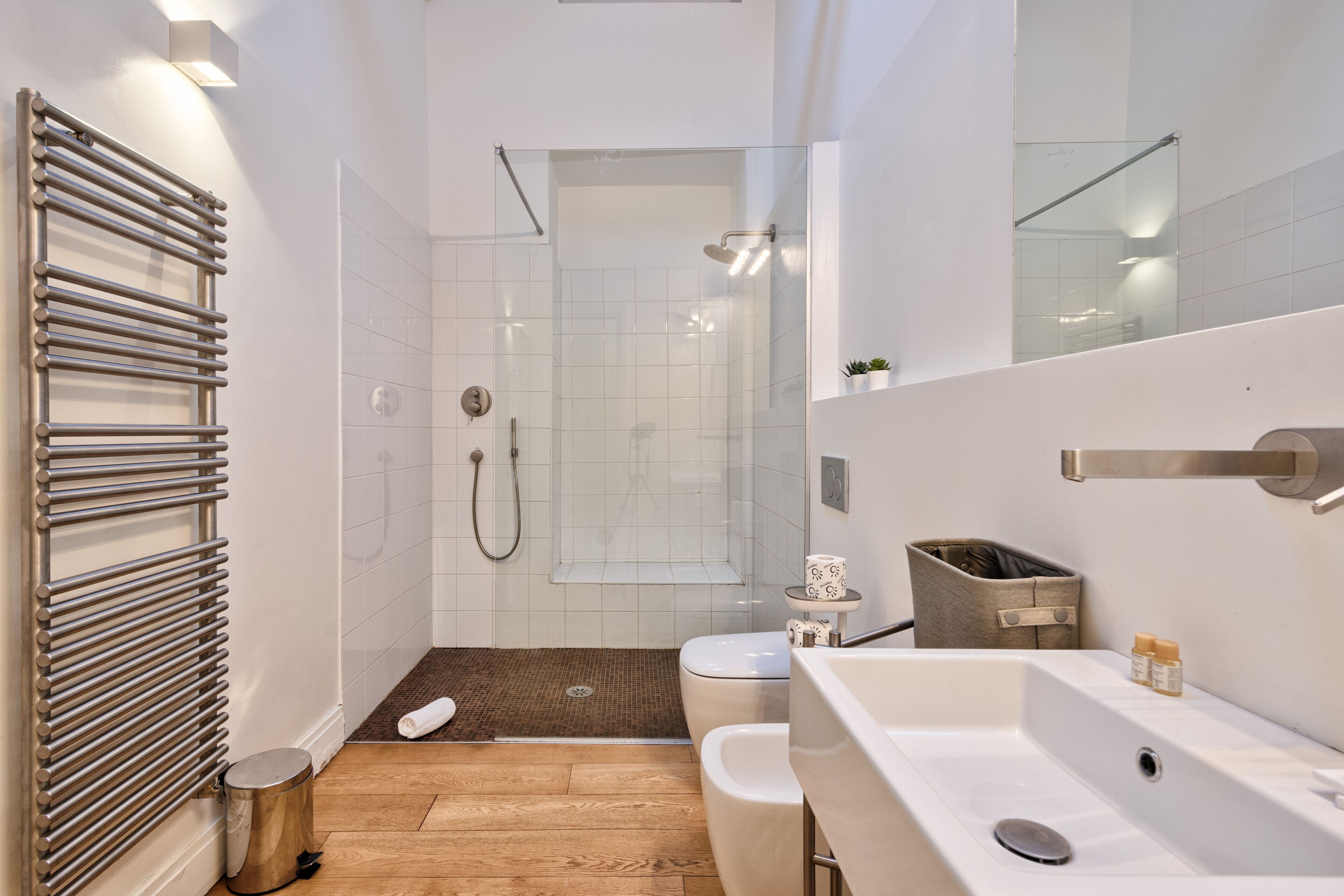 Ein modernes Badezimmer mit Duschkabine aus Glas, einem weißen Waschbecken und einem Handtuchhalter.