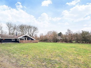 A single-story house with a fenced yard, a clear sky, and leafless trees.