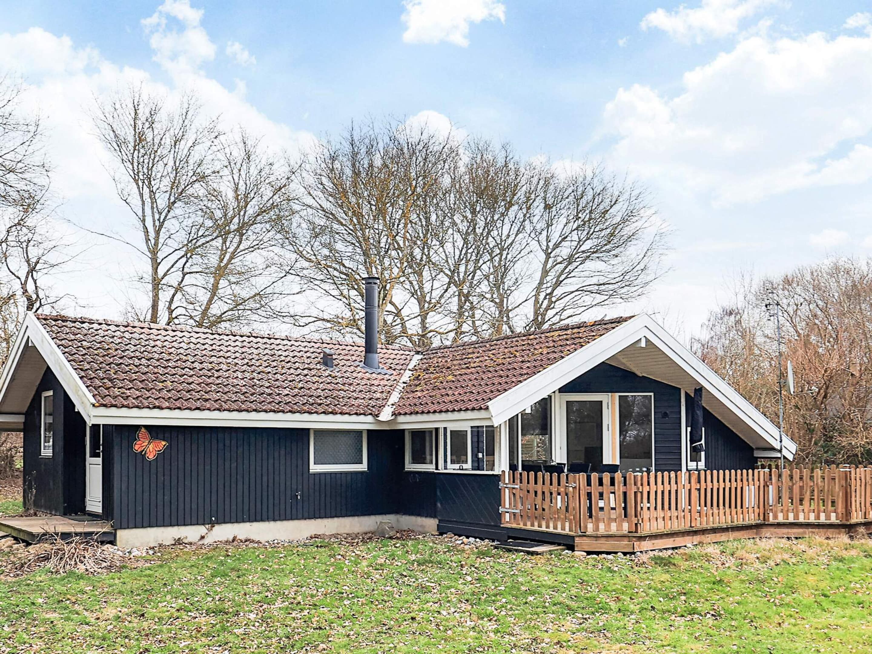 A two-story house with a tiled roof, a wooden deck, and a fenced yard.