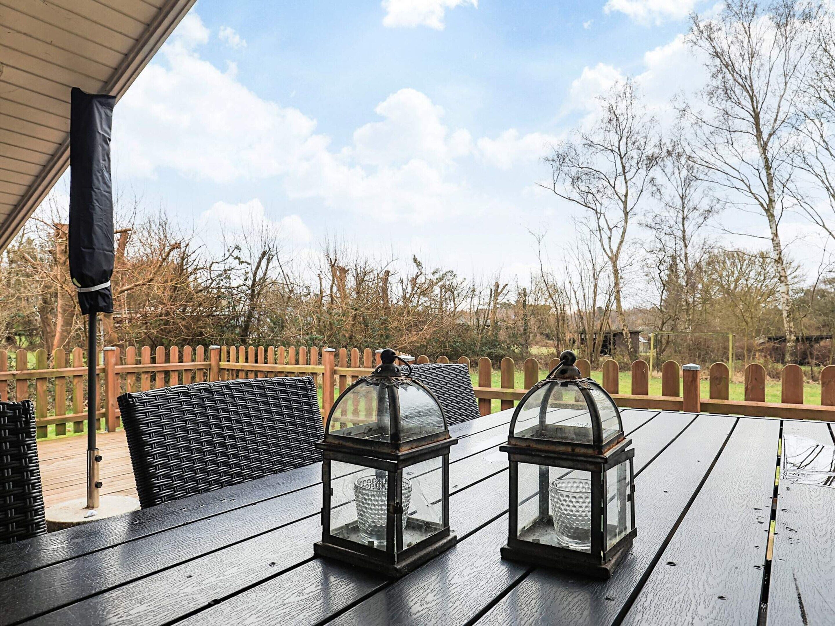 A wooden deck with two lanterns and a bench.