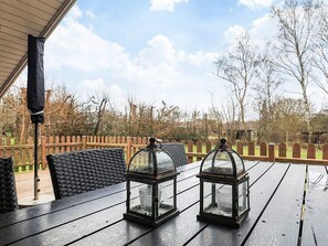 Een houten terras met twee lantaarns en een bank.