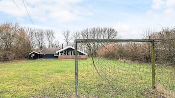 A fenced sports field with a goalpost, a wooden deck, and a house in the background.