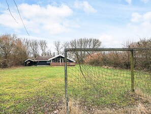 A fenced sports field with a goalpost, a wooden deck, and a house in the background.