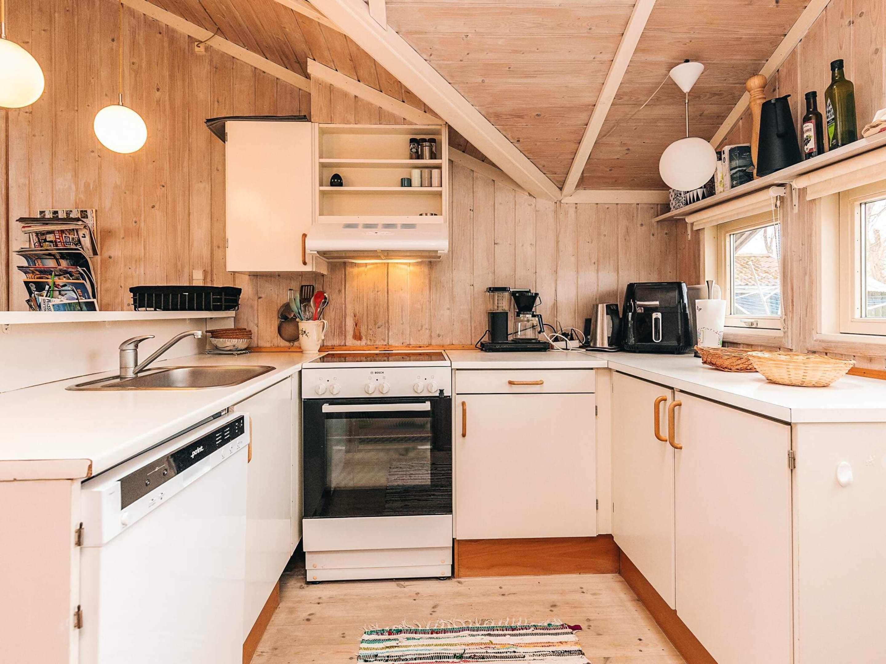 A kitchen with white cabinetry, a Bosch dishwasher, a stove, and a coffee maker.
